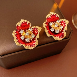 Macro detail of vintage red enamel flower earrings with crystal centers in a jewelry box