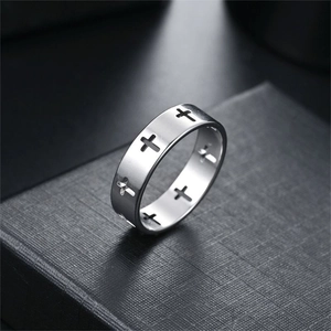 Detail of a minimalist silver ring featuring hollowed cross patterns on a dark box