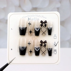 Macro shot of long coffin handmade press-on nails with 3D black bows and silver hearts