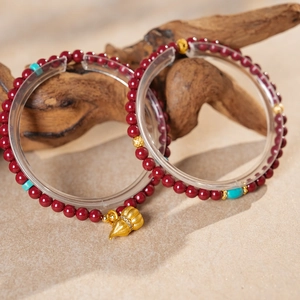 Detailed macro of cinnabar beaded bracelets with gold gourd pendant and turquoise accents