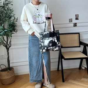 Borsa tote in tela tie-dye artistica con outfit casual e gonna di jeans in dettaglio