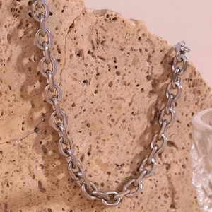 Macro shot of silver stainless steel thick link chain necklace on textured stone background
