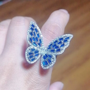 Detail of silver butterfly ring with blue gemstones and diamonds on hand model