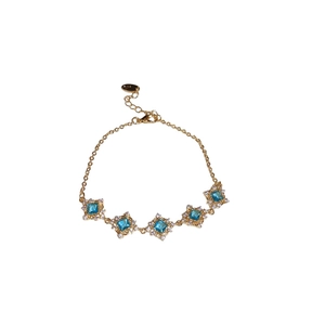 Elegant gold bracelet with square blue zircons and crystals on a pure white background