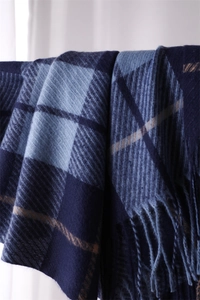 Close-up of soft blue plaid scarf texture with woven tassels and cashmere-like fabric