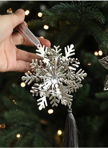 Silver snowflake ornament with crystal center and silk tassel on a Christmas tree