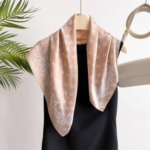 Pink silk scarf with paisley print hanging on a black rack for professional styling