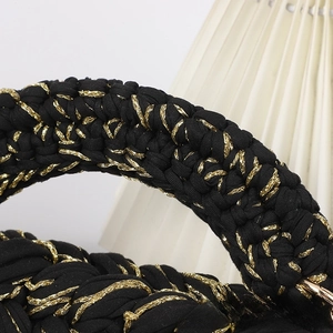 Close-up of black and gold hand-crocheted crossbody bag with fine metal buckle detail