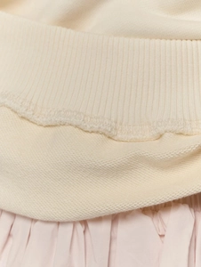 Détail macro des coutures sur les poignets côtelés et le molleton de coton crème