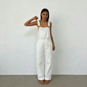 Detail of white denim overalls featuring metal buckles and large front cargo pockets