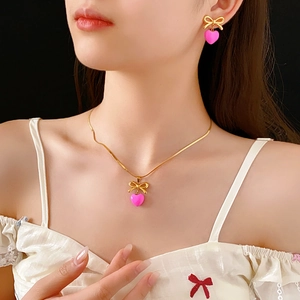 Gros plan sur l'ensemble collier et boucles d'oreilles à nœud doré et cœur rose