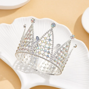 Macro shot of silver metal crown cake topper with iridescent rhinestones on shell tray
