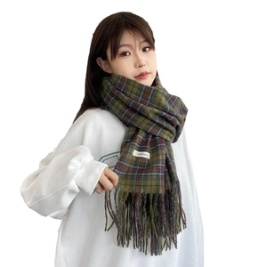 Thick green plaid cashmere-like scarf with tassels shown on a model for winter warmth