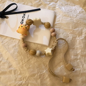 Macro detail of hand-woven bracelet featuring a yellow ceramic cat and wooden beads
