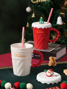 Macro view of Christmas ceramic mugs with knit texture, festive lids, and striped straws
