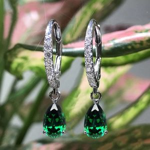 Vista macro di orecchini in argento con zircone verde a goccia e micro-pave di cristalli