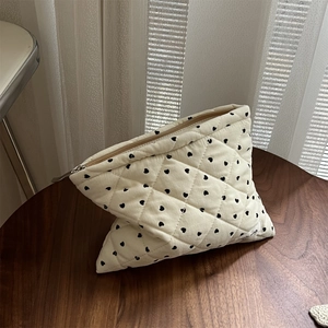 Close-up of quilted heart pattern makeup bag on a wooden table with soft lighting