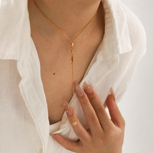 Détail d'un collier en Y plaqué or 18 carats avec zircone porté sur une chemise blanche