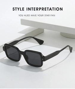 Macro shot of black square frame sunglasses with metal rivets on minimalist white pedestal