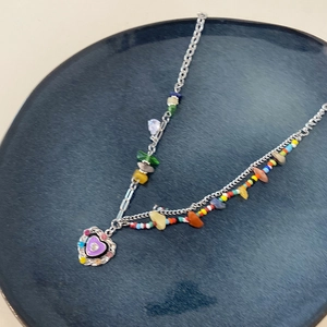 Close-up of heart-shaped purple pendant with colorful crystals on a beaded necklace