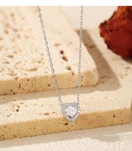 Macro shot of silver heart pendant necklace with shimmering crystals on stone surface