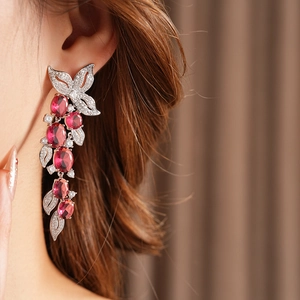 Macro de boucles d'oreilles pampilles en argent avec pierres rouges et feuilles serties