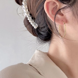 Detailed close-up of golden twist rope hoop earrings on model for a minimalist style