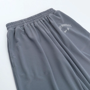 Détail du pantalon gris foncé avec taille élastique et texte imprimé sur la poche