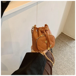 Close-up of caramel bucket bag with drawstring, chain strap and camellia metal buckle