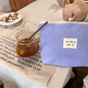 Detailed close-up of a purple corduroy pouch with a woven colorful logo label