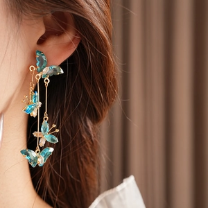 Gros plan de boucles d'oreilles pampilles dorées avec papillons en cristal bleu