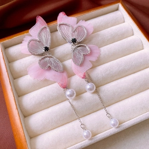 Close-up of pink gradient butterfly earrings with rhinestone wings and pearl tassels