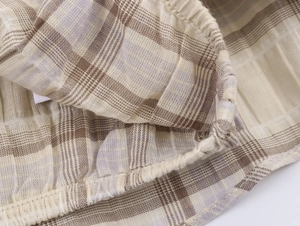 Gros plan sur le tissu à carreaux beige avec ourlet élastiqué et coutures précises