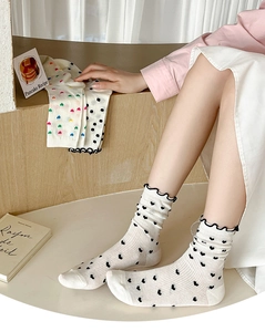 Close-up of white mesh ankle socks with black heart pattern and ruffled trim edges