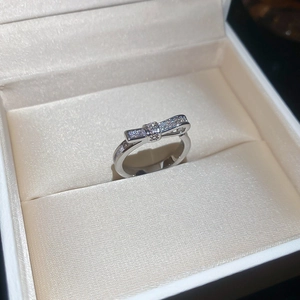 Detail of a sparkling bow-shaped ring with pavé-set zircons in a beige jewelry box