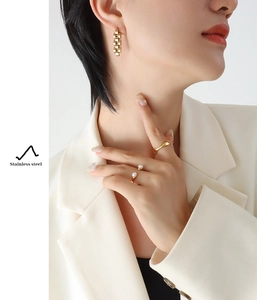 Details von vergoldeten Edelstahl-Ohrringen und Ring-Set an einem weiblichen Modell