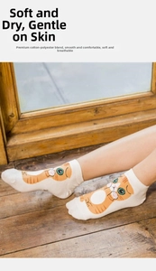Detail of white cotton socks featuring a cute orange cartoon cat pattern on the fabric