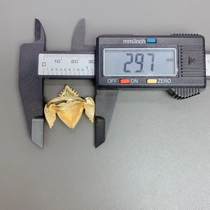 Caliper measuring the 29.7mm width of a gold heart ring with wings and red oil detail