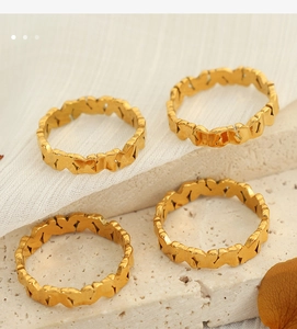 Detailed macro view of four gold-plated butterfly patterned rings on a stone background