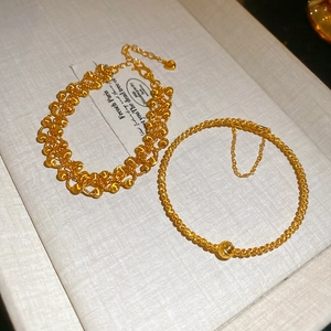 Detail of 24K gold-plated beaded bracelets with heart pendant and frosted bead