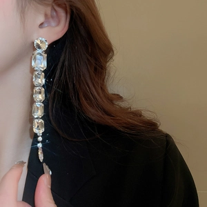 Close-up of silver long tassel earrings with sparkling square crystals on a model