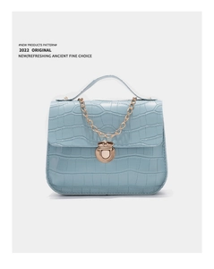 Detail of light blue crocodile pattern small handbag with gold chain and clasp lock