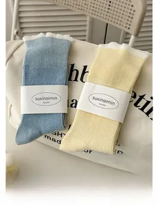 Close-up of ruffled cuff crew socks in sky blue and soft yellow with ribbed texture