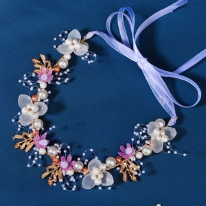 Detail of bridal headband with purple flowers, pearls, and gold leaves on blue background