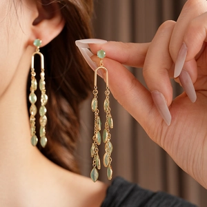 Gros plan de boucles d'oreilles pendantes dorées avec pierres œil de chat et feuilles