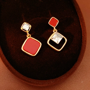 Macro shot of 18k gold plated diamond earrings with red square zircon details