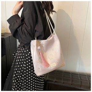 Detail of pink embroidered tote bag with floral patterns and silk tassel charm