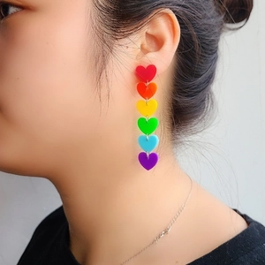Side view detail of a model wearing colorful rainbow acrylic heart tassel earrings