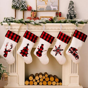 Gesteppte weiße Weihnachtssocken mit rot-schwarzem Karomuster hängen an einem Kamin dekor