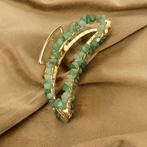 Detail of handmade banana hair claw with gold metal wire and green natural crushed stones